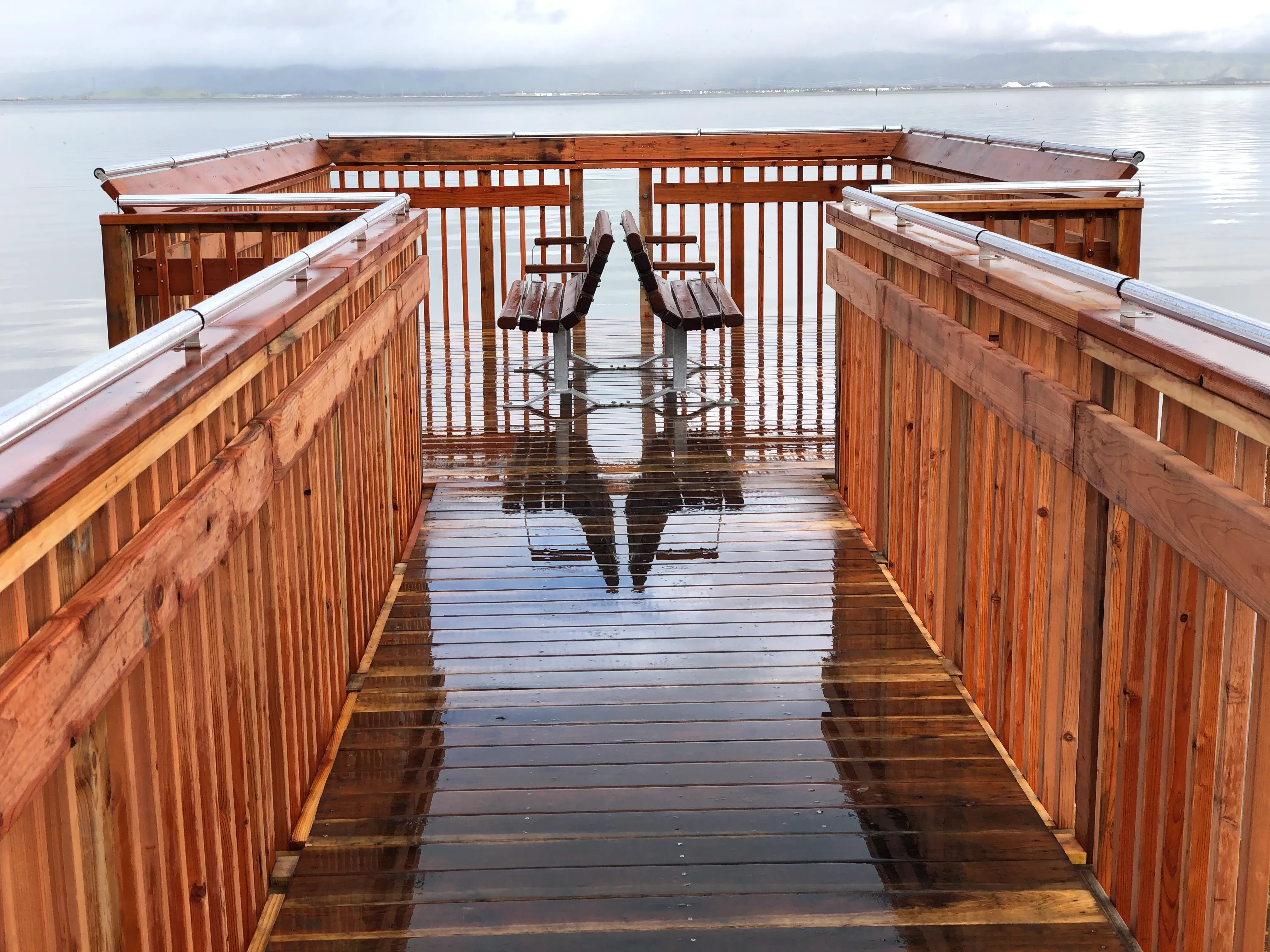 A reflective wooden lake dock just after rain
